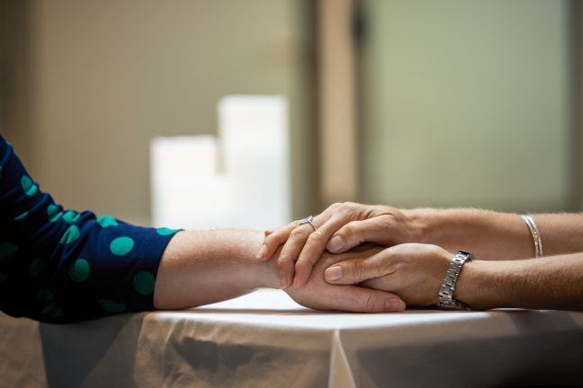 2 people holding hands in comfort