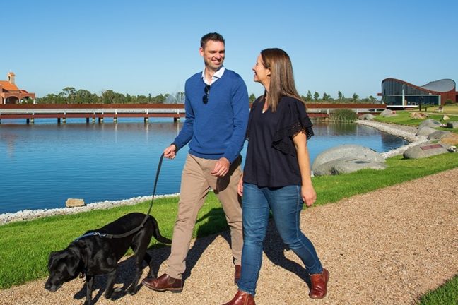 Man and woman walking dog by the lake