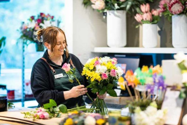 An SMCT florist creates a beautiful, bright floral arrangement for a customer