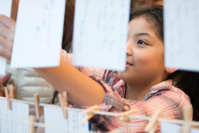 A child hangs up a tribute card in remembrance of a loved one