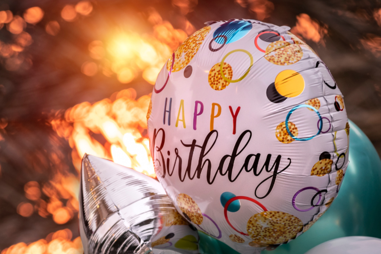 A photograph of balloons with 'happy birthday' printed on them.