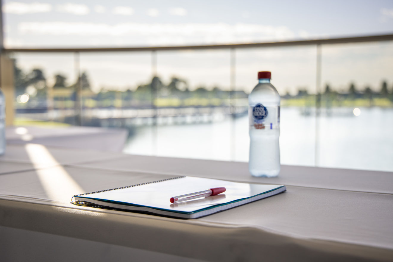 A bottle of water, note pad and pen at a table set up for a corporate function at the Sanctuary, Bunurong Memorial Park