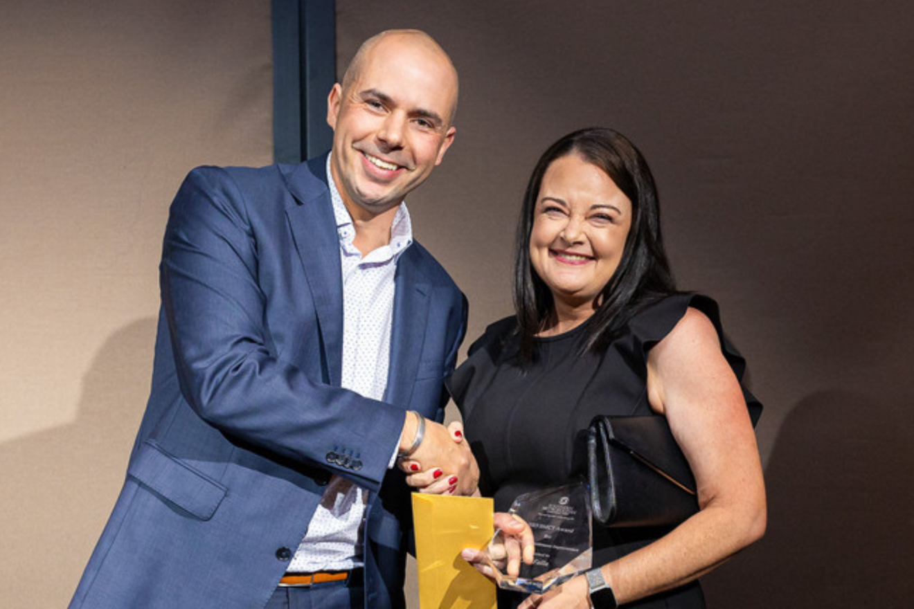 A photograph of SMCT's Strategic Product Manager Lisa Falla, smiling, as she poses with her award alongside SMCT Chief Customer Officer Damian Ramondetta