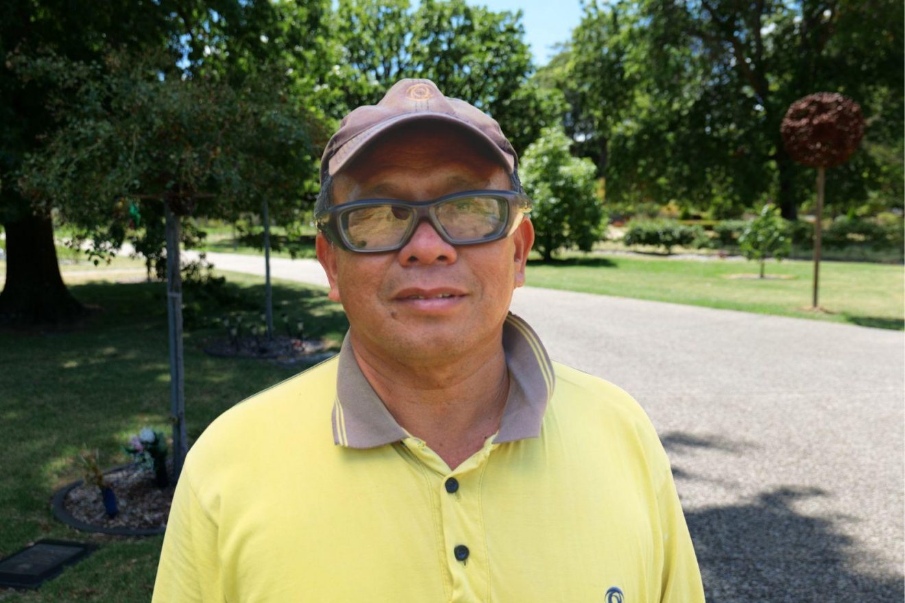 A man in high-vis standing in front of gardens.