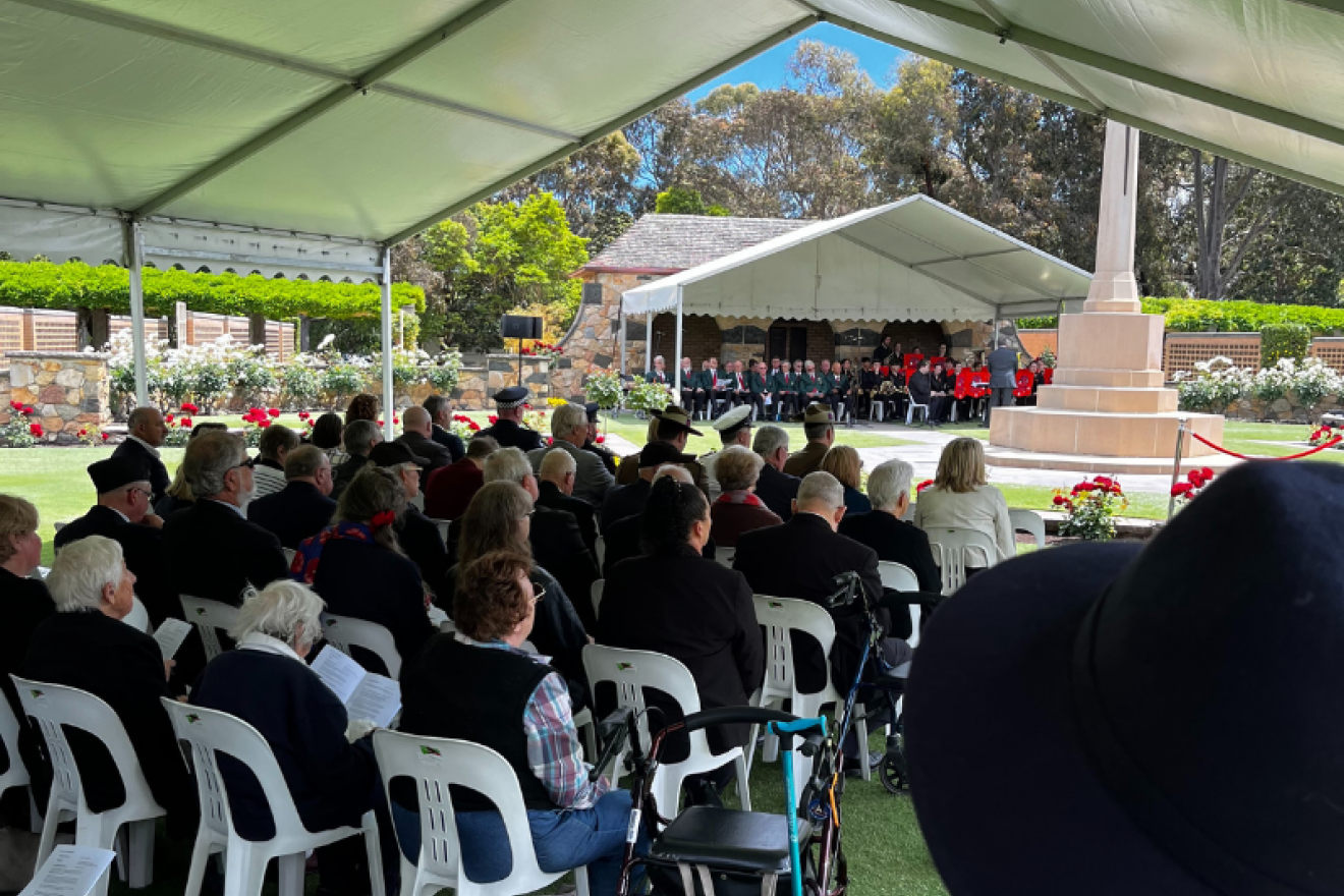View from within the event marque as audience members observe the ceremony from chairs seated in rows.