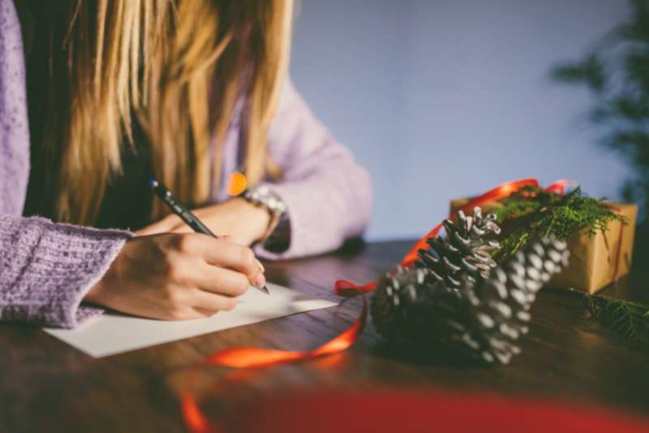 A close-up of a woman's hand as she writes a Christmas card