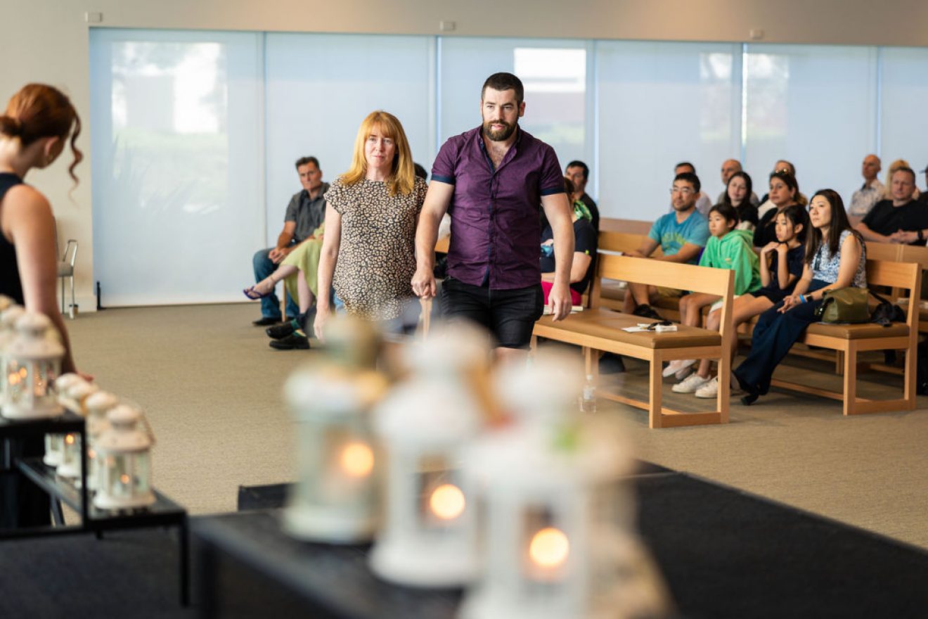 A couple holding hands approach a table with lanterns.