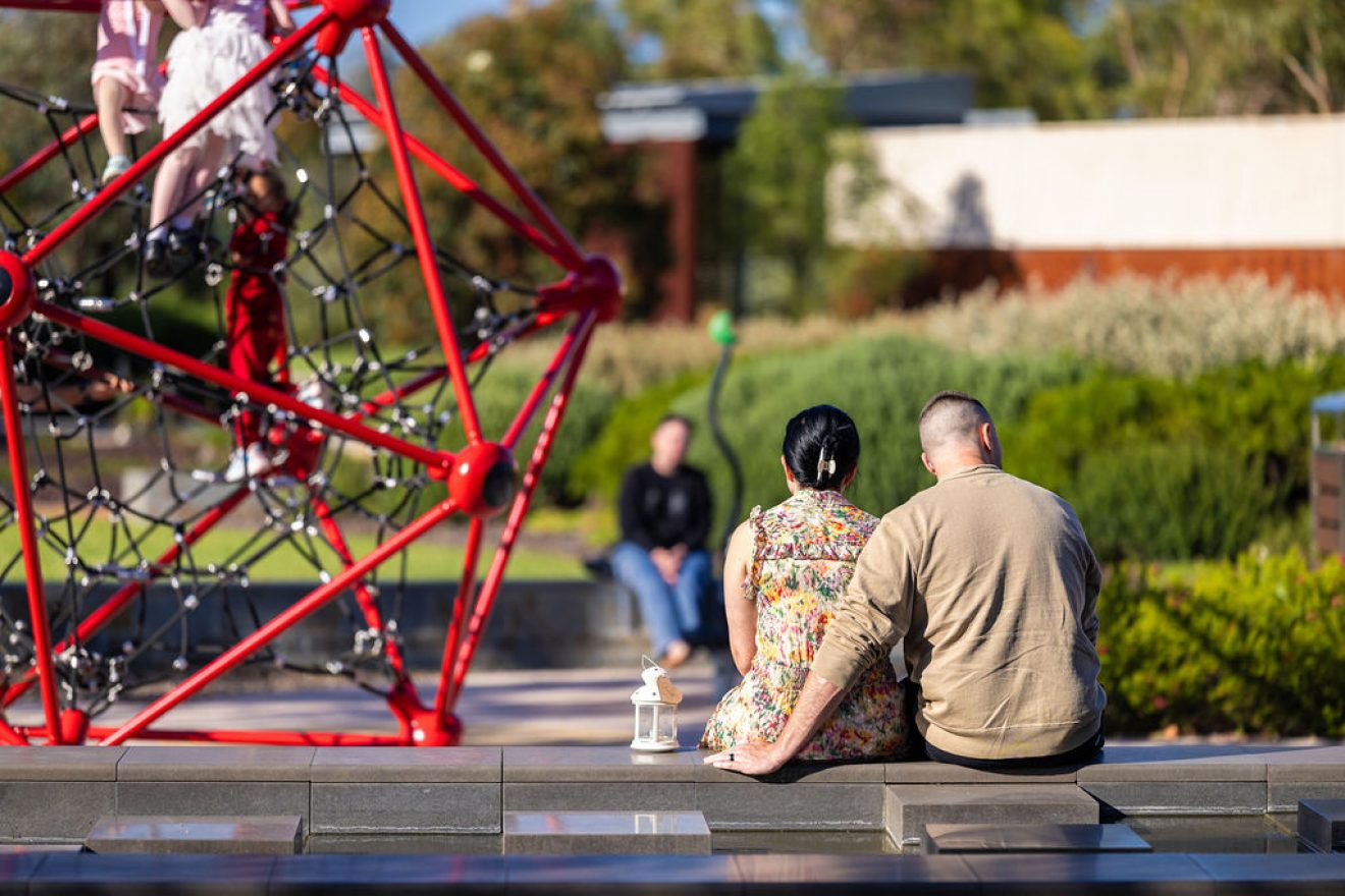 Couple sitting by playground equipment.