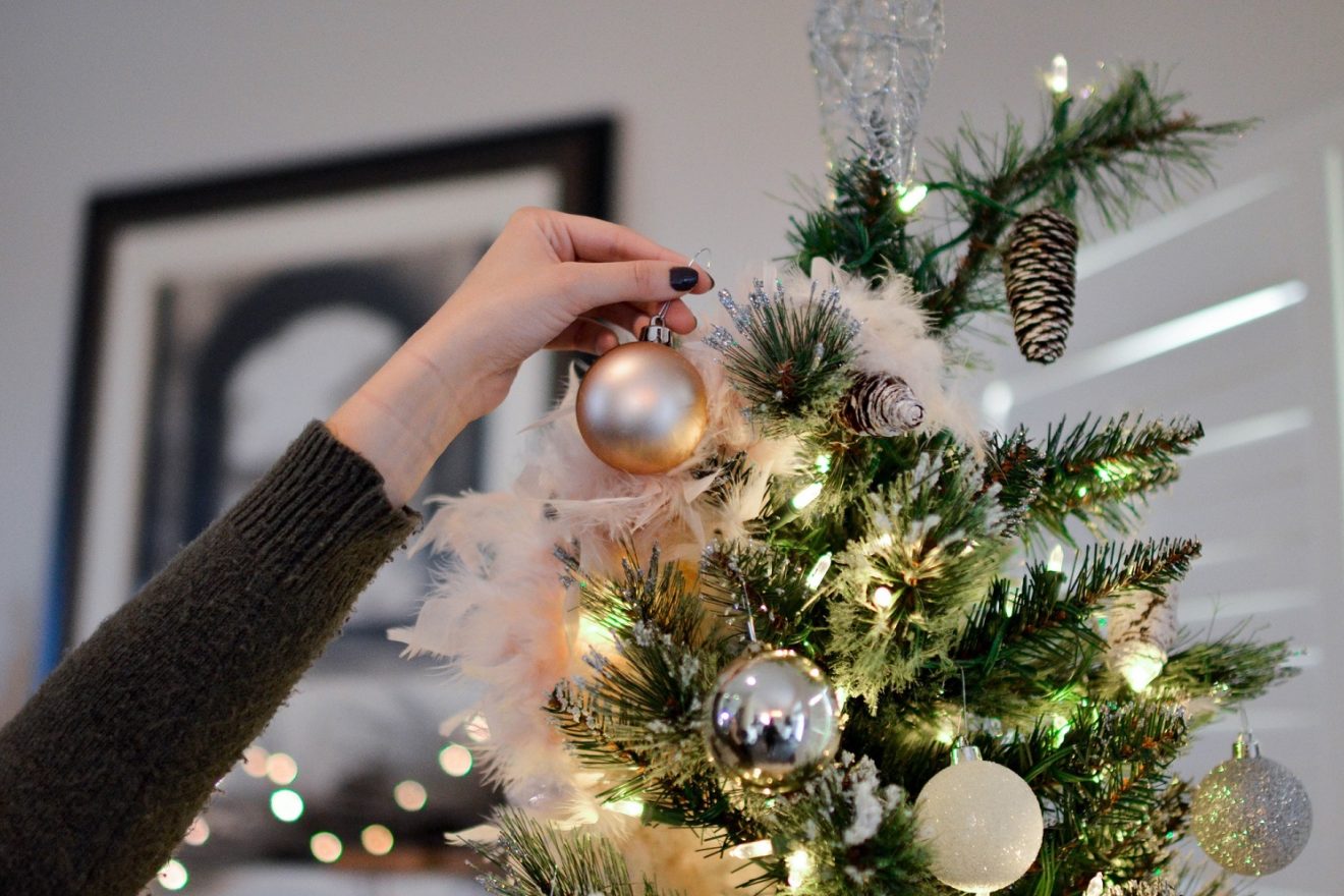 placing an ornament on a christmas tree