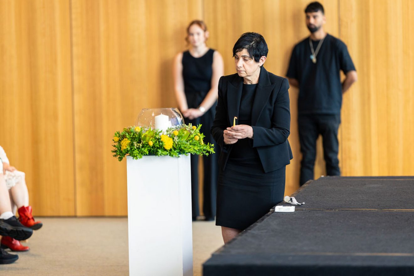 Woman approaches plinth with lit candle in hand.